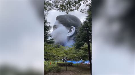 metal cover of giant floating head above house|giant face floating above park.